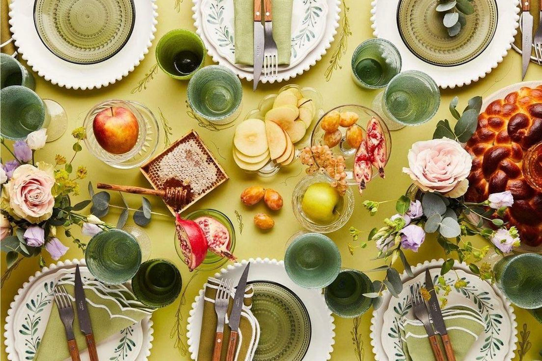 Rosh Hashanah table with apples, honey, pomegranate, challah, and flowers