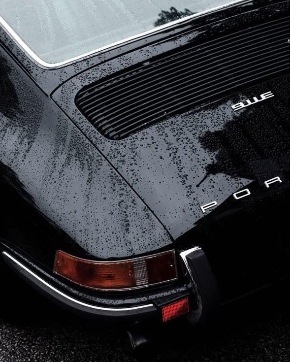 Close-up of a black Porsche car with visible branding on a dark background