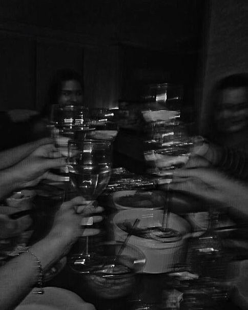 Group of people toasting with glasses in a dimly lit room