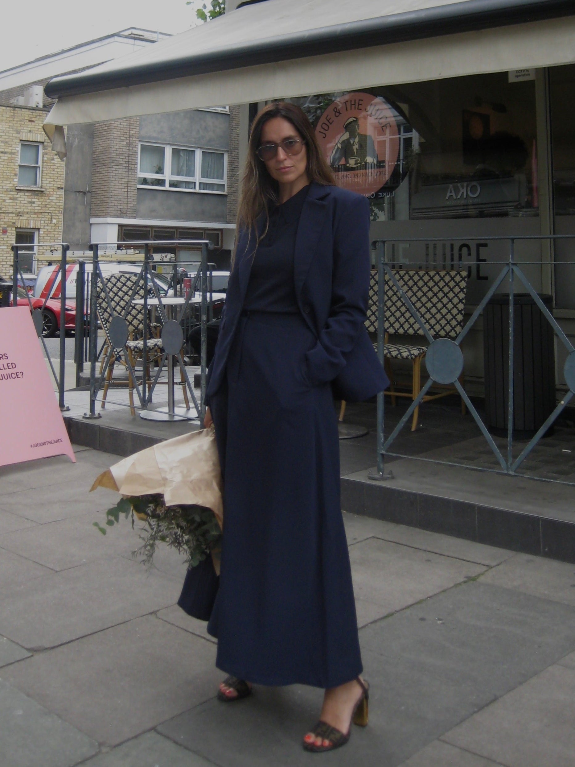 Woman in a navy blue outfit standing outside a store named 'Joe & The Juice'.
